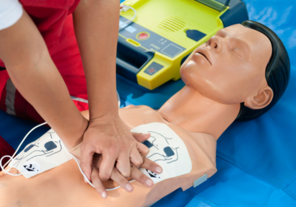 Person performing chest compressions on CPR mannequin 