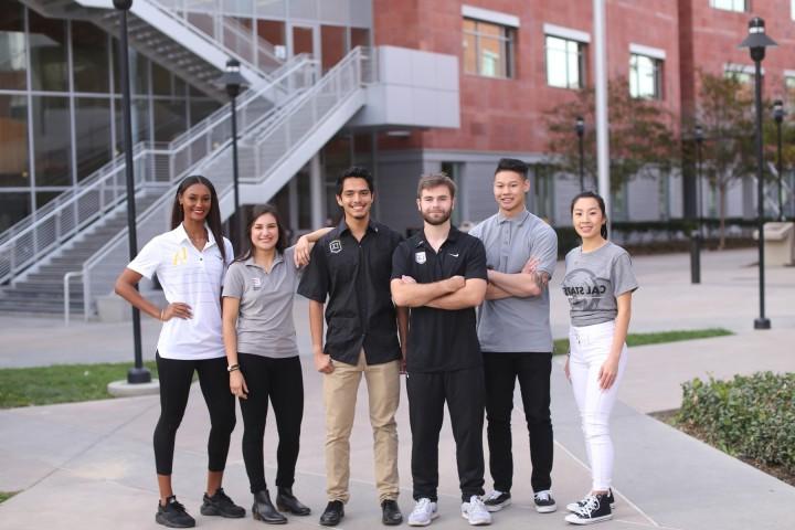 Group of students wearing Cal State LA branded clothing standing outsize of La Kretz Hall
